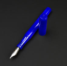 Load image into Gallery viewer, A cobalt blue fountain pen with a matching cap placed behind it on a dark gray background.