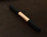 Franklin-Christoph Model 55 Pentium FP - Black Copper SE pen rests on a dark brown, subtly embossed surface.