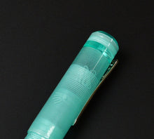 Load image into Gallery viewer, A translucent mint green pen cap with a metallic clip, photographed diagonally against a solid black background.