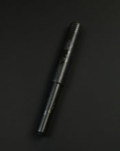 Load image into Gallery viewer, The Franklin-Christoph Model 40 M Black Pen Society fountain pen rests on a dark background.