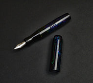 A pocket 45 OPS SE - Black Magic by Franklin-Christoph rests uncapped on a black textured surface—sleek and elegant.