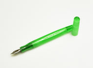 A Franklin-Christoph Model 65 Stabilis Kerry Green SE fountain pen with its cap off, placed beside it on white.