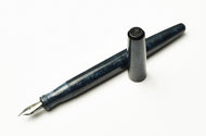 A Franklin-Christoph Model 65 Stabilis Diamondcast Blue pen, uncapped, rests on a white background.