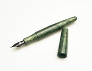 A Franklin-Christoph Pocket 66 Fountain Pen - Diamondcast Green, uncapped, lies on a white background.