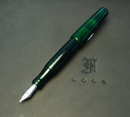 A Franklin-Christoph pocket 66 Fountain Pen in Solid Emerald rests by an F and three diamond shapes on black.