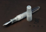 A Franklin-Christoph Pocket 66 Fountain Pen in Solid Ice rests uncapped on a dark surface near a gothic letter and diamonds.